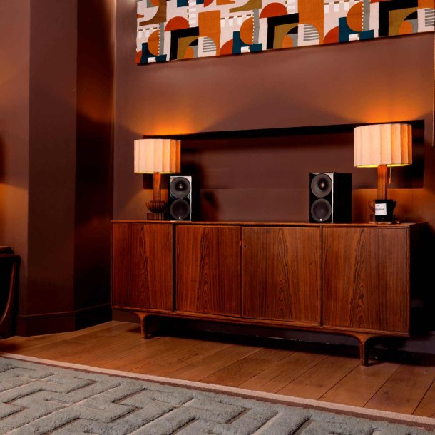 Et s�t Monitor Audio Radius 3 4G i sort h�jglans placeret p� et stort m�bel i rosentr�